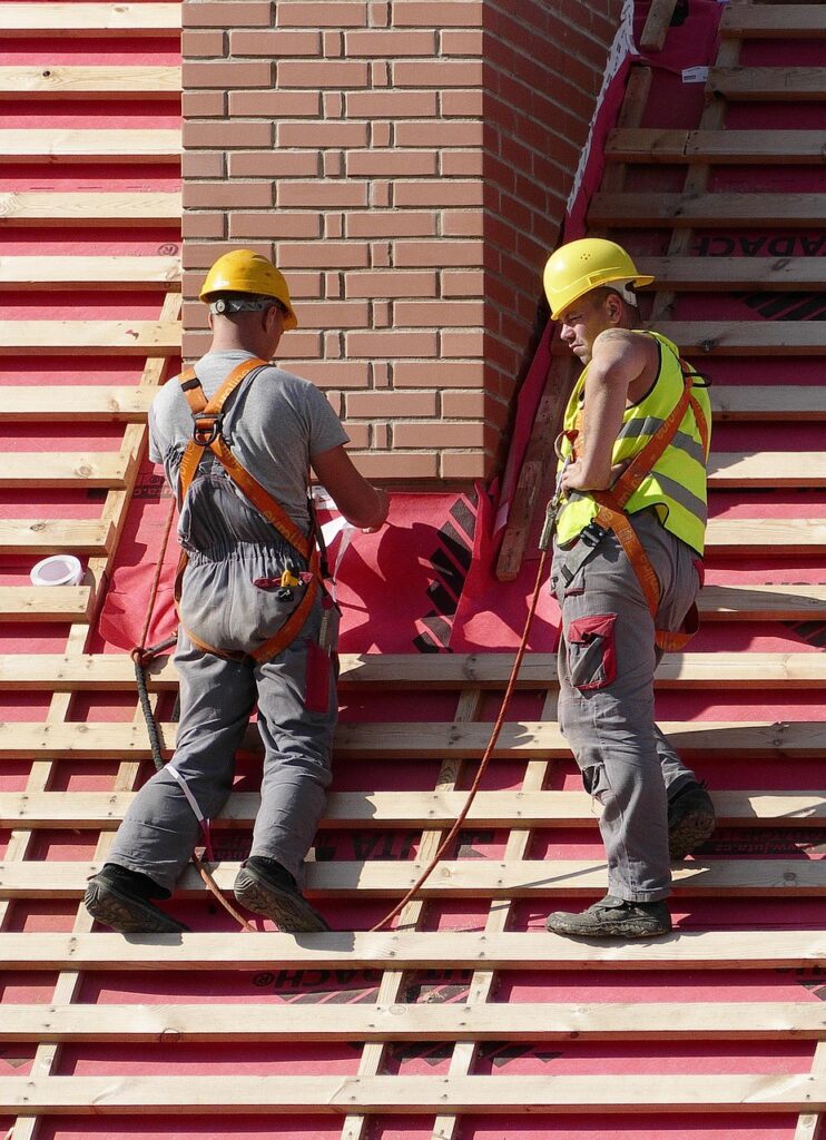 Construction workers: Two men in hard hats on a roof